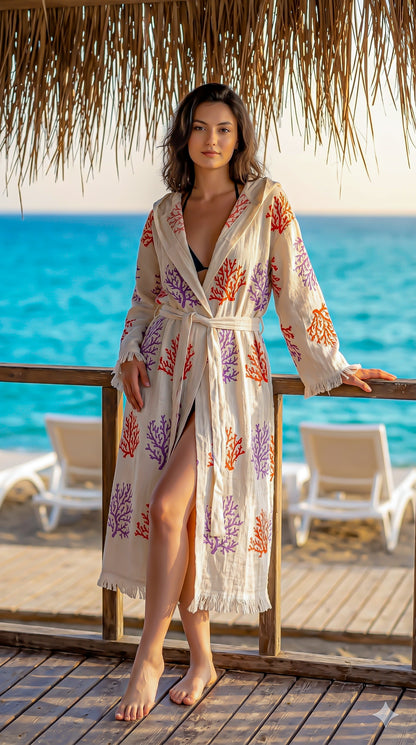Woman in a floral robe standing on a wooden deck by the ocean.