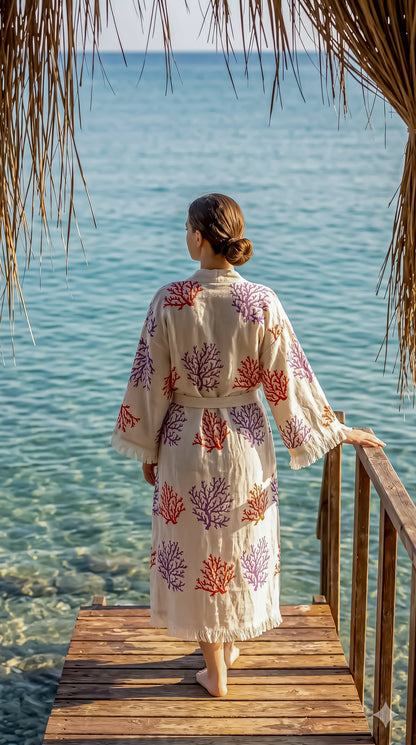 Woman in a floral dress standing on a wooden deck overlooking the ocean.