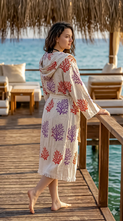 Woman in a floral kimono standing on a wooden deck by the water.